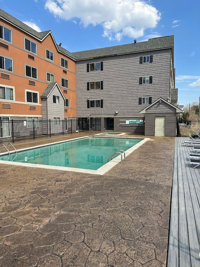 A large swimming pool is in front of a large building.