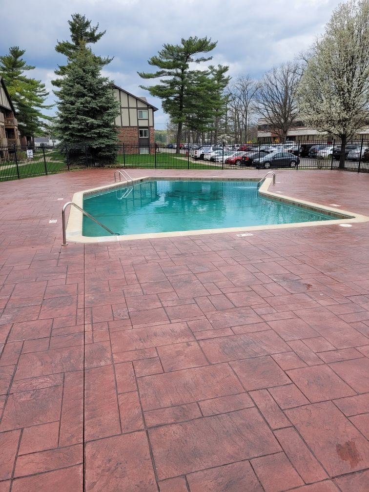 A large swimming pool is surrounded by a brick patio