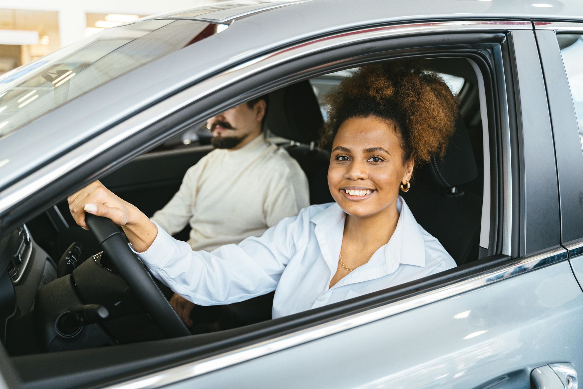 Person driving a car, hands on the steering wheel, with an instructor