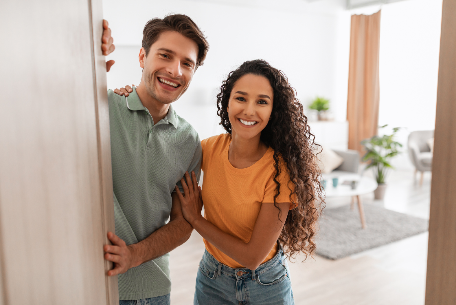 A man and a woman are peeking out of a doorway in a living room.