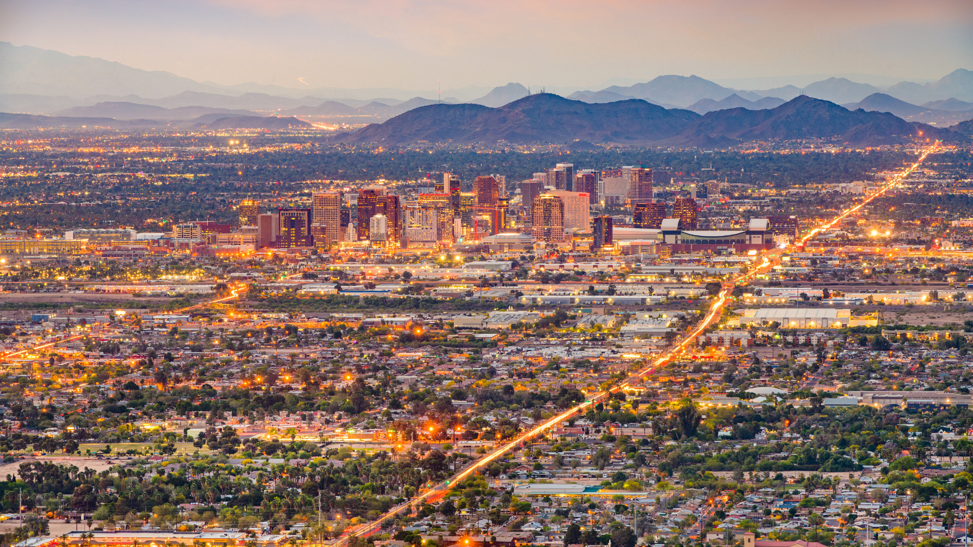 An aerial view of a city at night with mountains in the background.