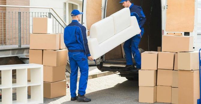 Moving team loading a white armchair into a truck full of boxes.