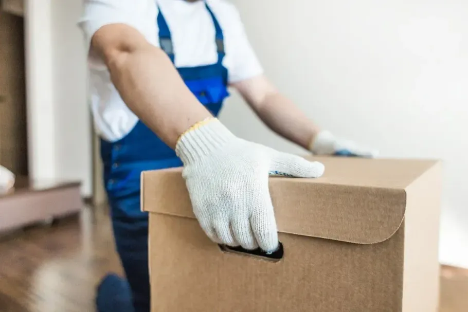 Close-up of a professional mover lifting a heavy cardboard box.