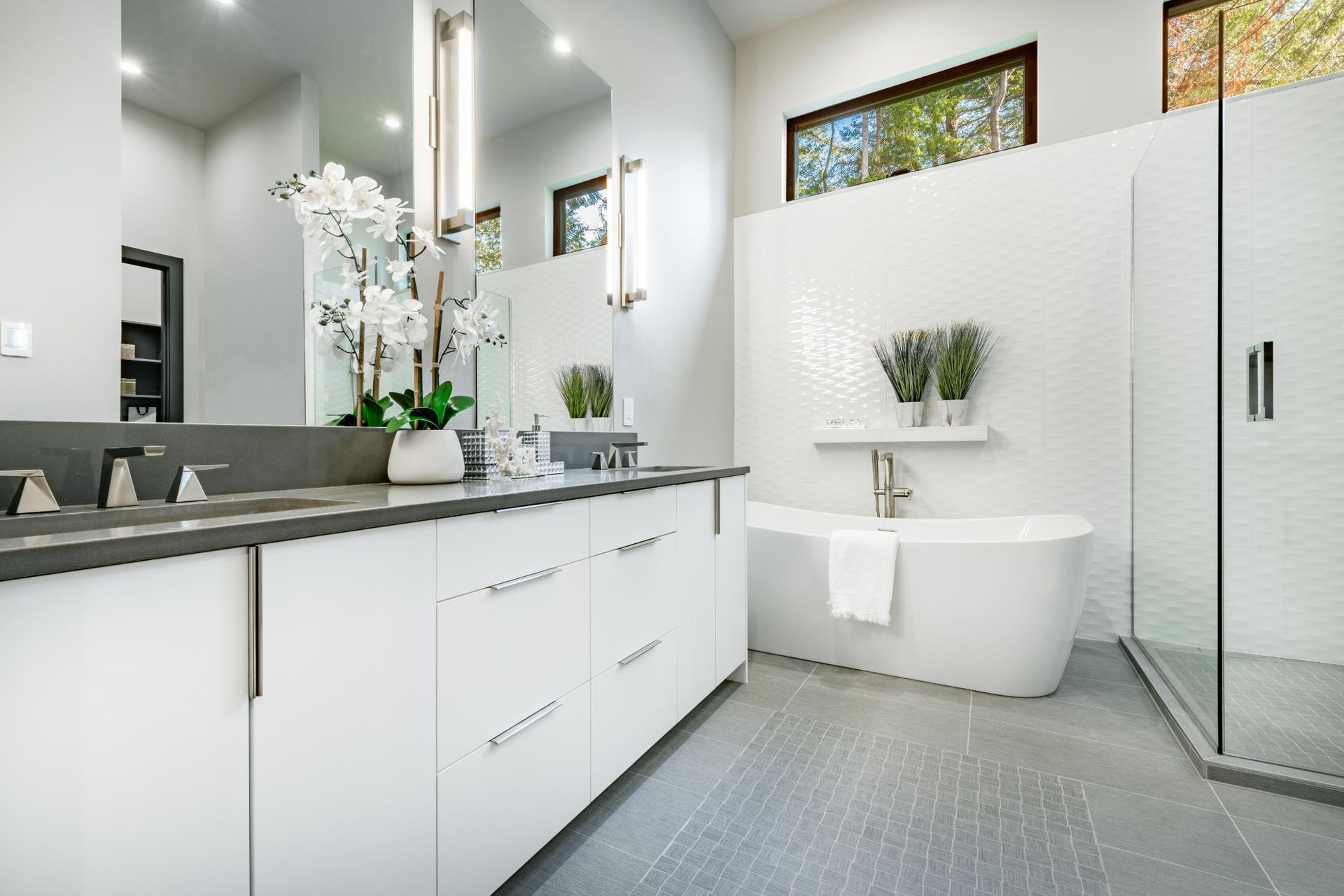 Modern bathroom with white cabinets, gray countertop, soaking tub, and walk-in shower.
