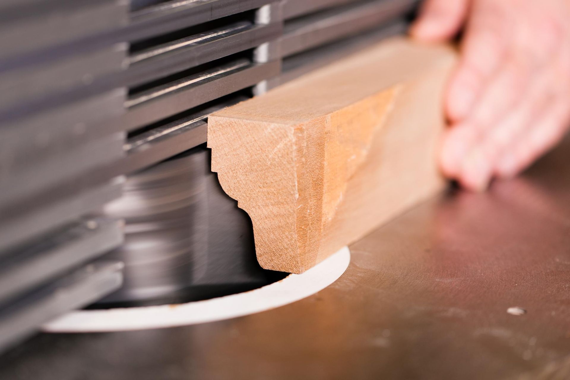 Woodworker using a router to shape the edge of a wooden block.