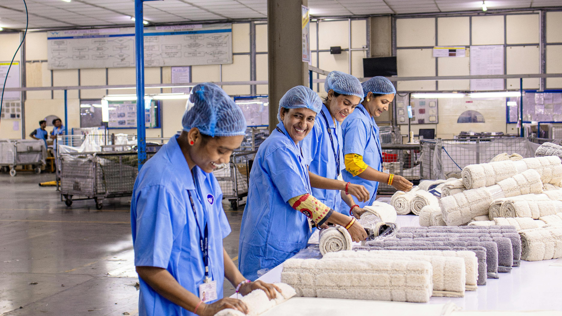 Workers in blue uniforms packaging noodles on a factory production line