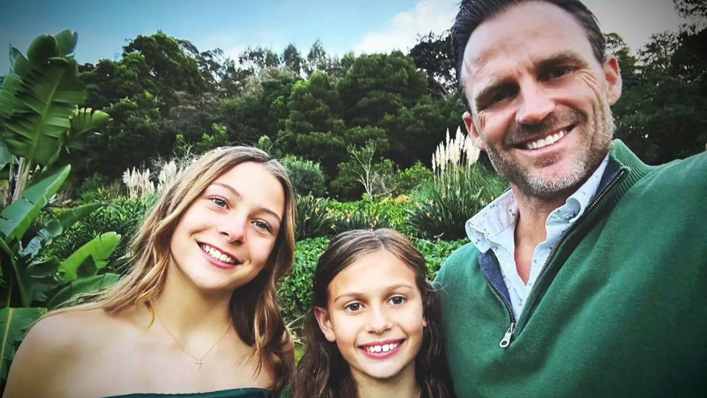 Three smiling people taking a selfie outdoors in a lush green garden