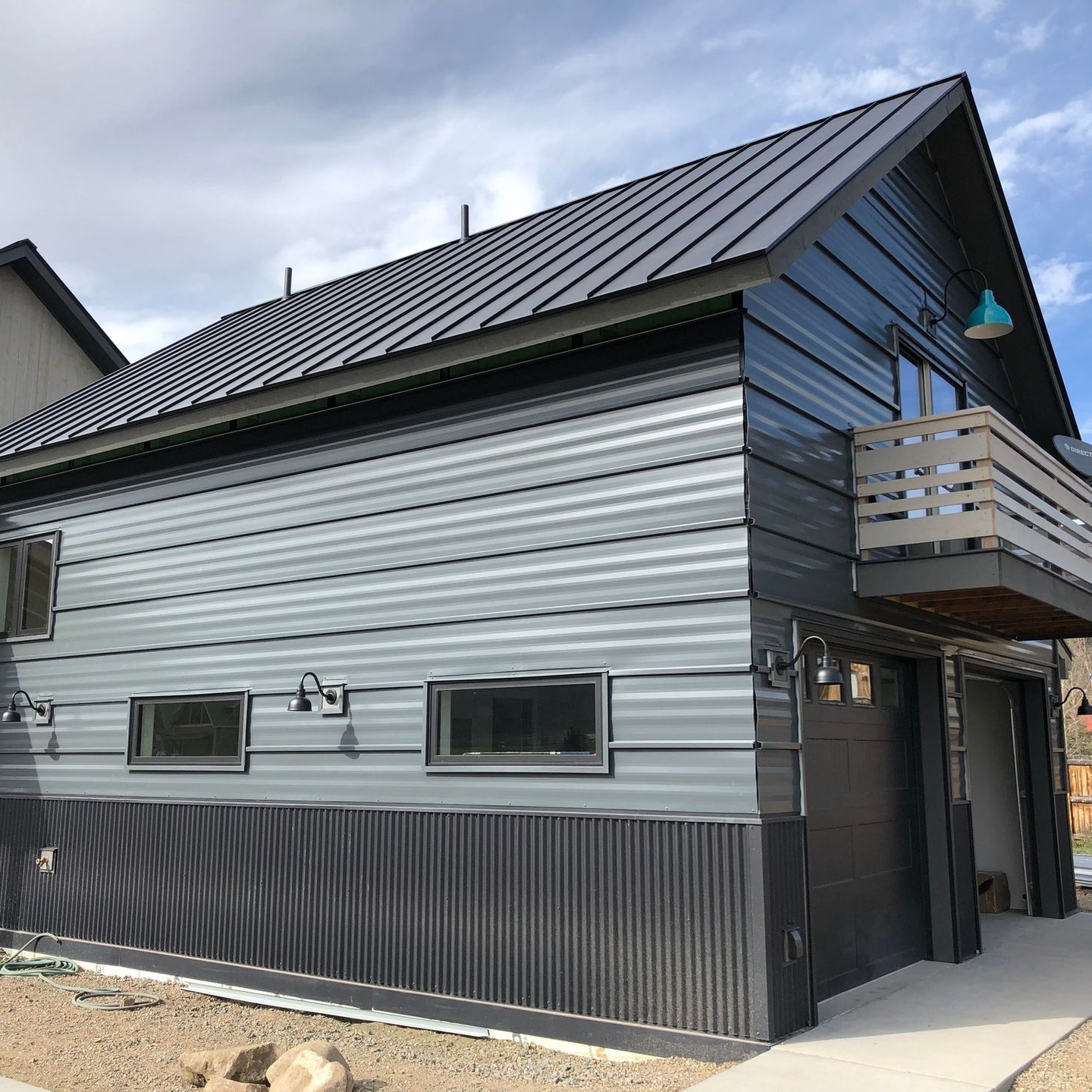 A gray house with a black roof and a balcony