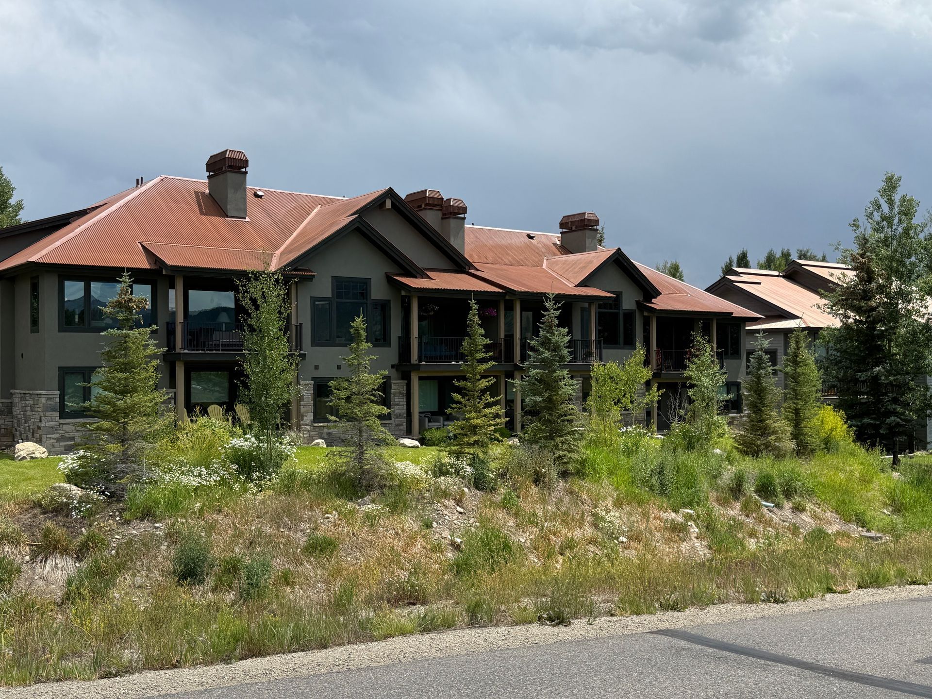 Multi-unit residential buildings with brown roofs and stone accents, under a cloudy sky.