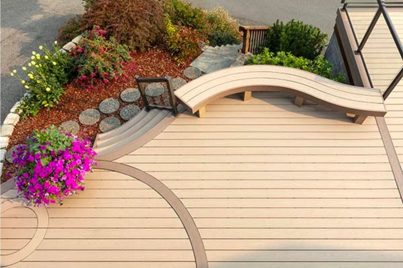 Terrasse beige incurvée avec banc intégré et parterre de fleurs coloré dans un jardin paysager