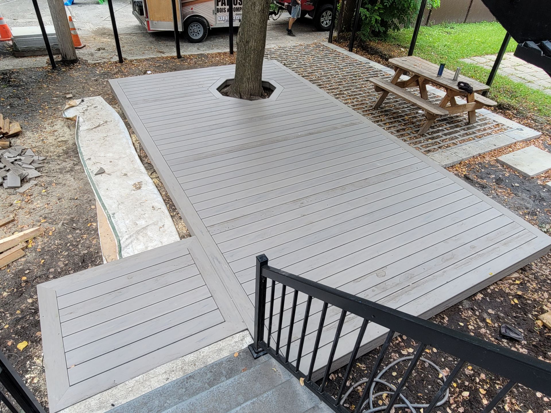 Plateforme en bois accessible avec ouverture dans un arbre, à côté d'escaliers et d'une rambarde, près d'un sentier de parc