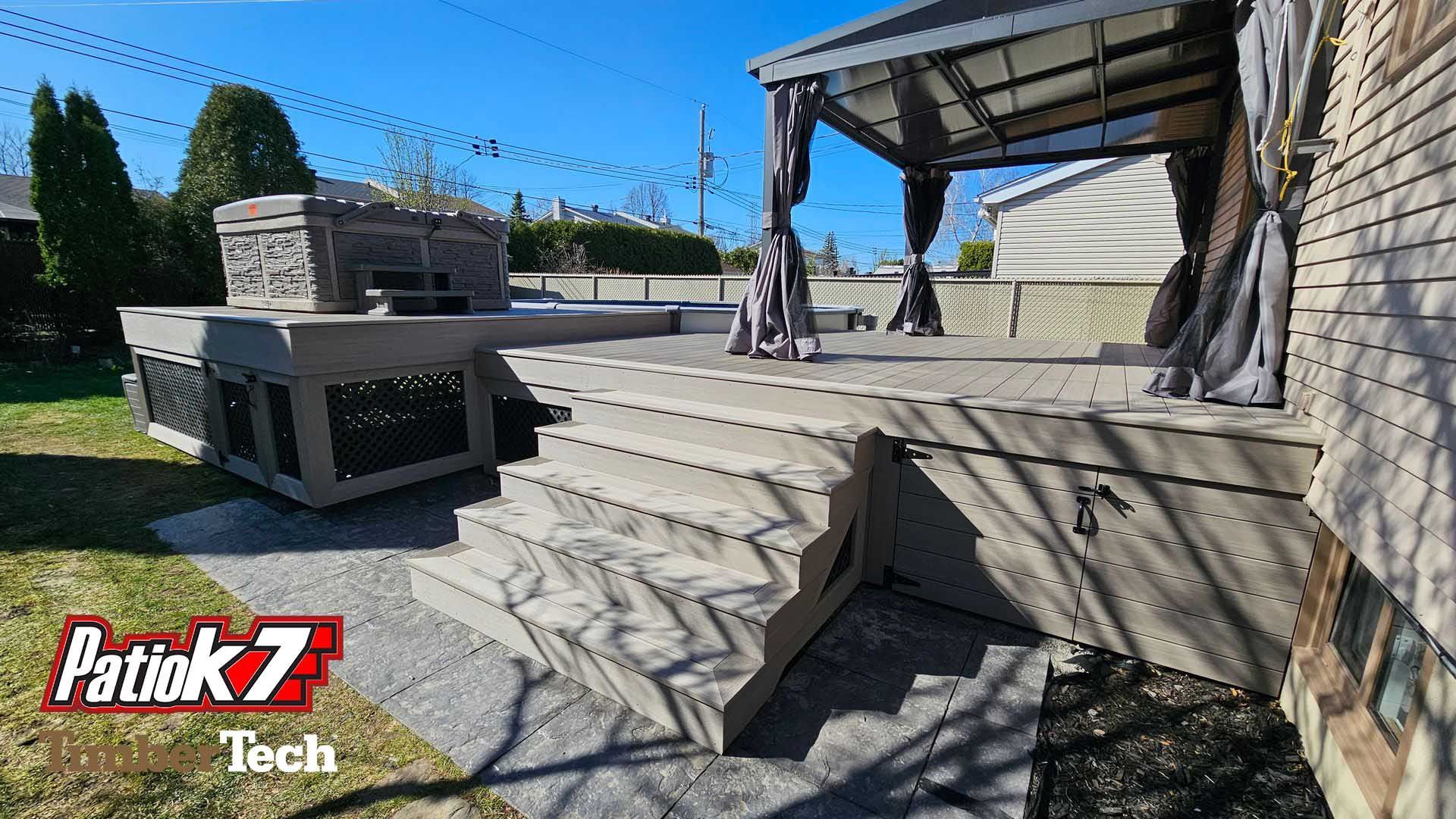 Terrasse arrière avec marches en pierre, terrasse surélevée et pergola couverte à côté d'un mur de briques.