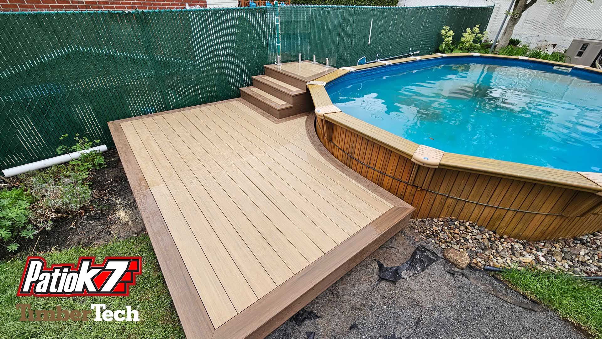 Terrasse en bois jouxtant une piscine hors sol avec des marches et une clôture verte assurant l'intimité dans une cour arrière.