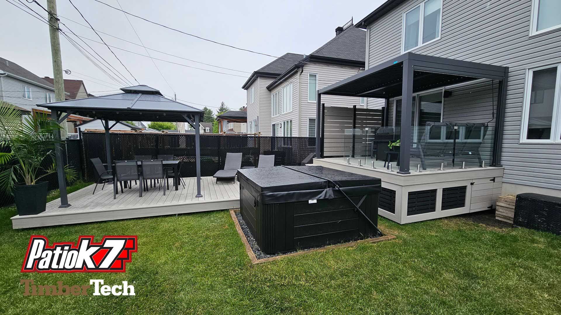 Terrasse arrière avec mobilier de jardin noir, un gazebo et une pelouse à côté d'une maison