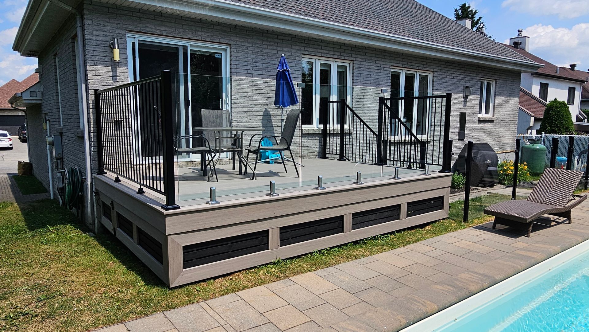 Terrasse arrière avec mobilier de jardin, parasol et piscine à côté d'une maison