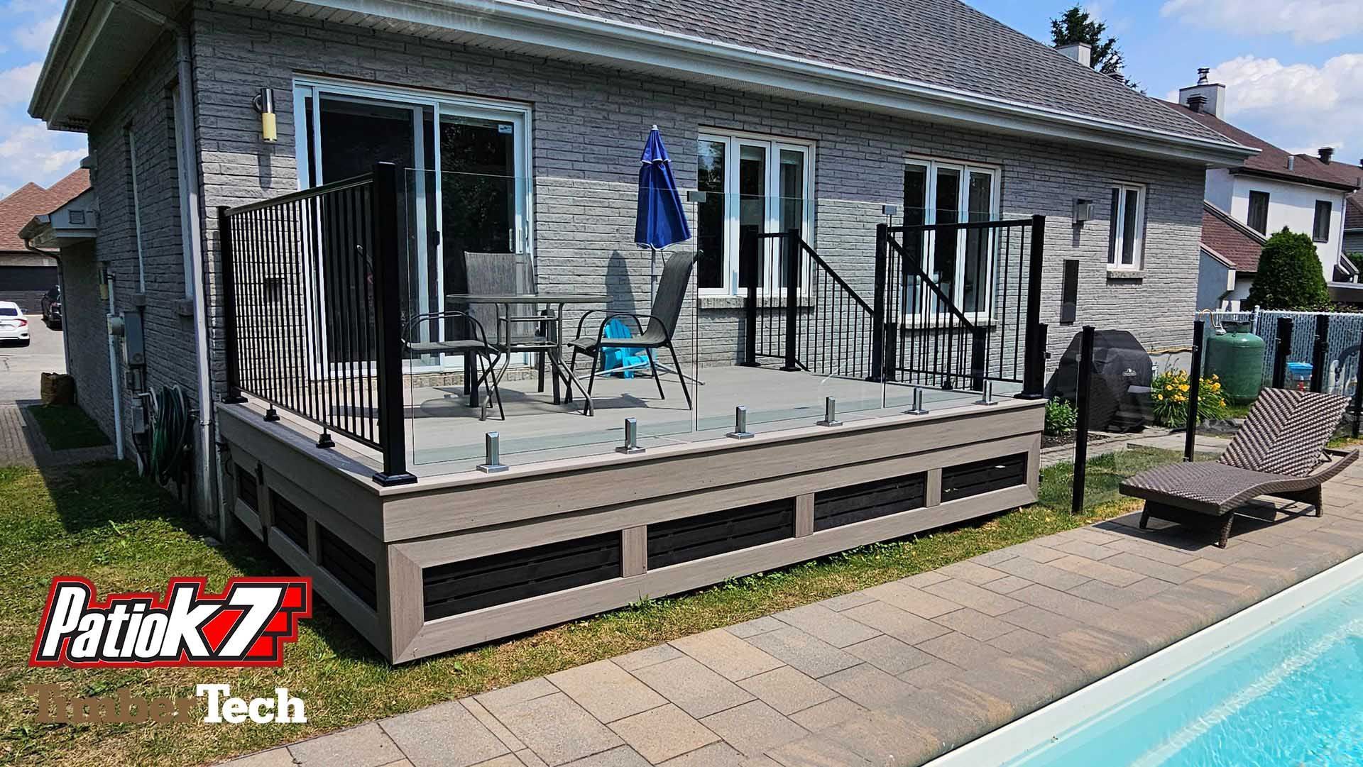 Terrasse arrière avec mobilier de jardin, parasol et piscine à côté d'une maison