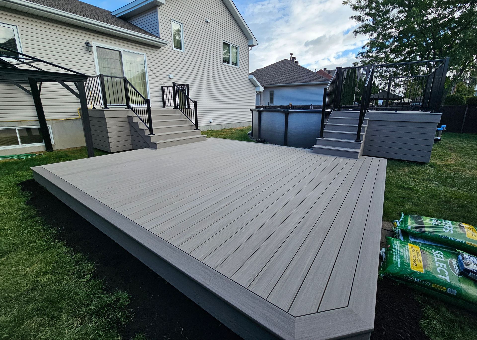 Grande terrasse grise attenante à une maison et une piscine hors sol dans un jardin