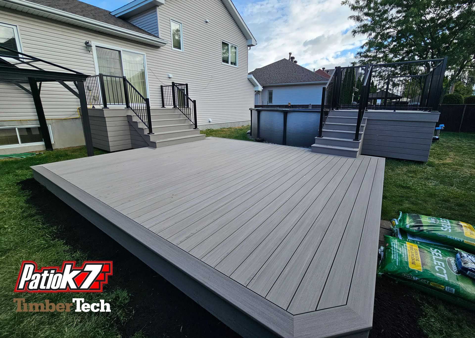 Grande terrasse grise attenante à une maison et une piscine hors sol dans un jardin