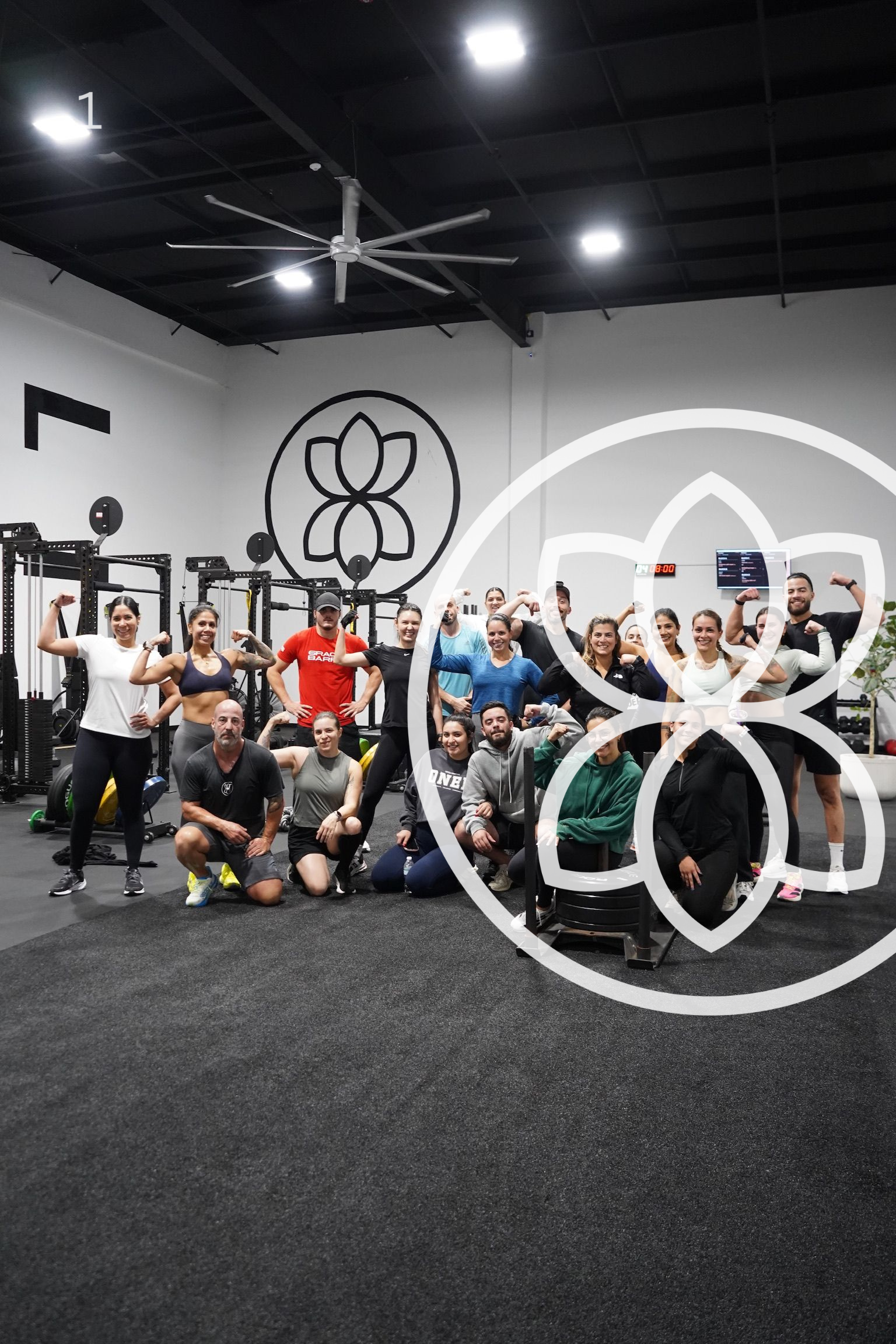 Group posing in a CrossFit gym, with a large ring-shaped mural on the wall.