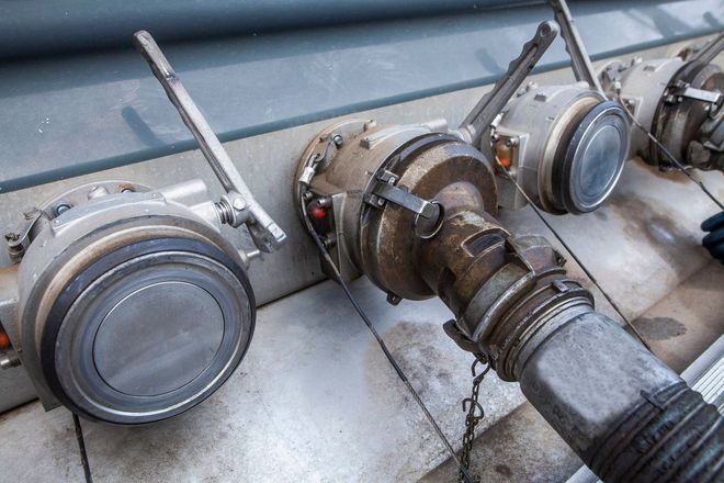 Fuel nozzles attached to a metal surface. Silver and gray, with levers and hoses.