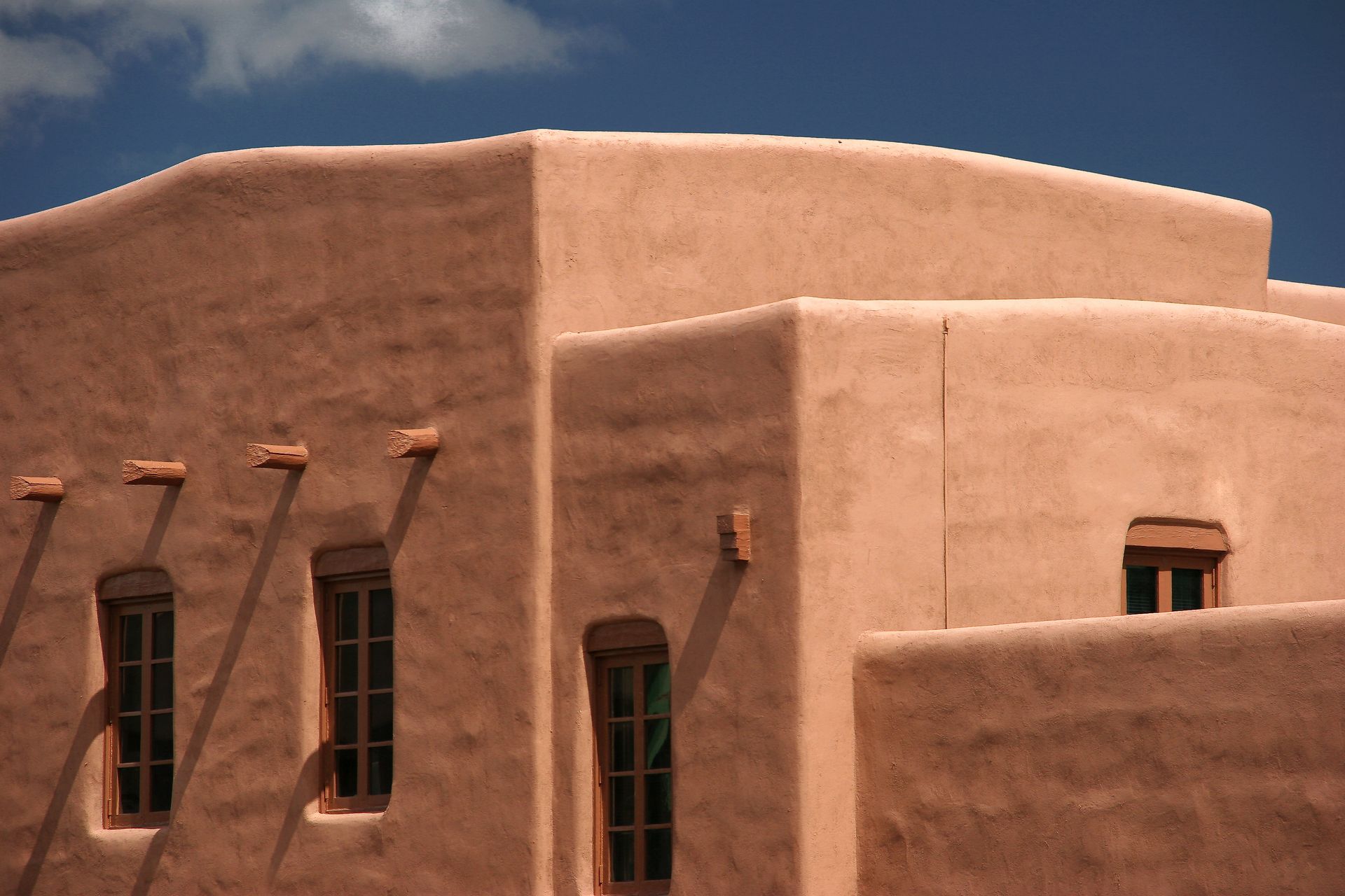 Adobe-style stucco building with tan walls, green-trimmed windows, and protruding wooden beams Adobe-style stucco building with tan walls, green-trimmed windows, and protruding wooden beams