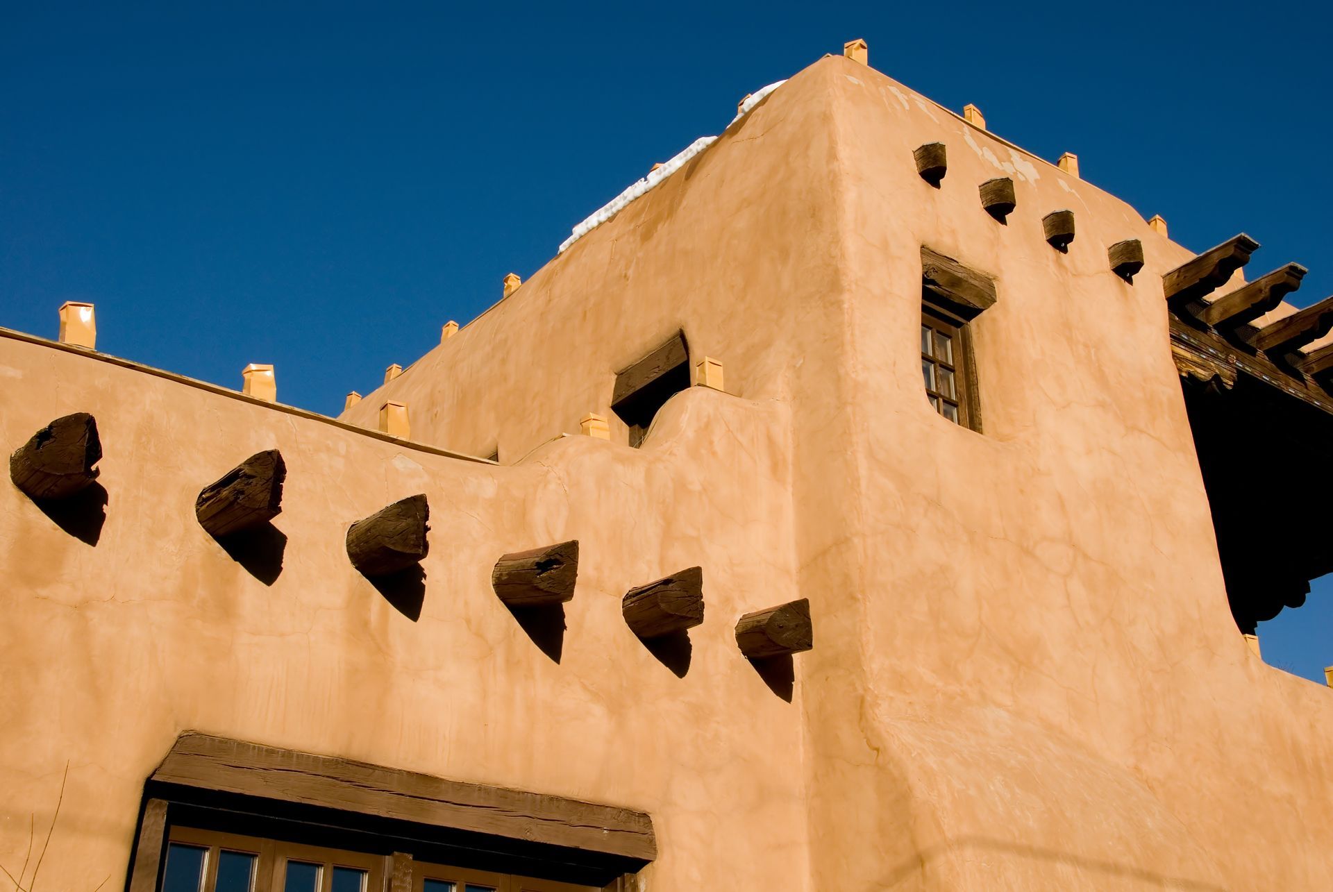 Tan adobe building with triangular openings against a clear blue sky Tan adobe building with triangular openings against a clear blue sky