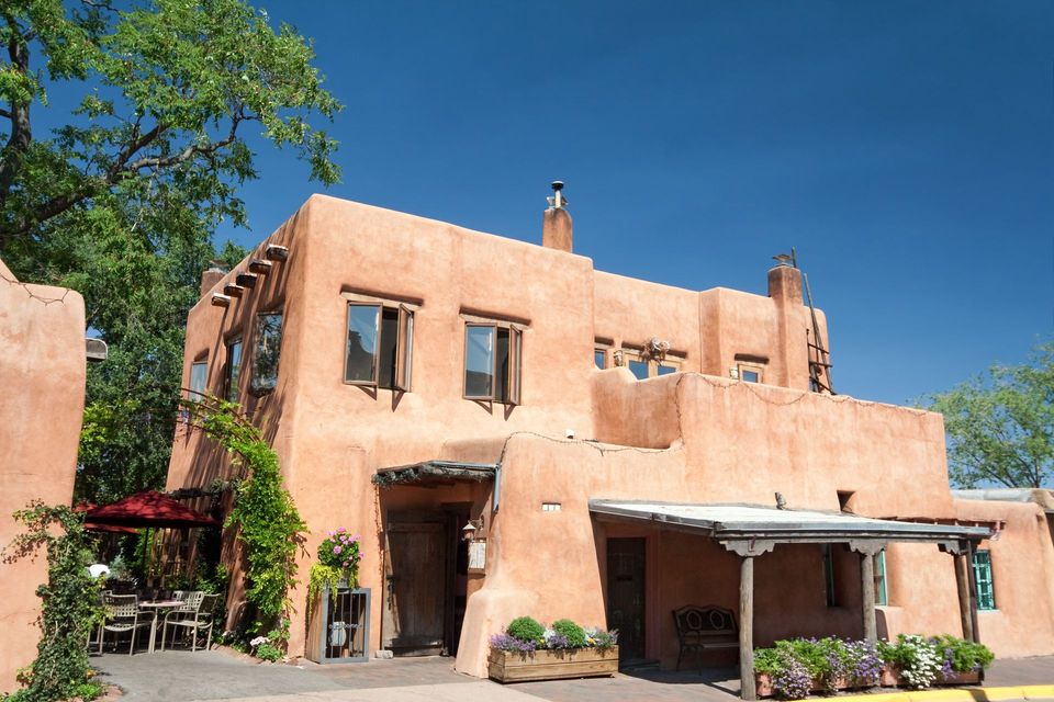 Sunlit peach stucco building with a covered patio, potted plants, and clear blue sky Sunlit peach stucco building with a covered patio, potted plants, and clear blue sky