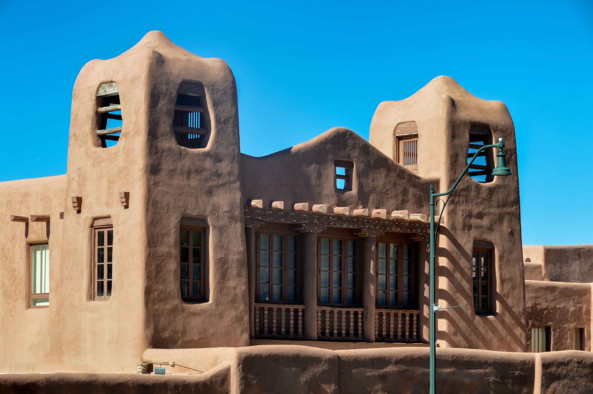 Adobe-style building with rounded towers and blue windows under a bright blue sky