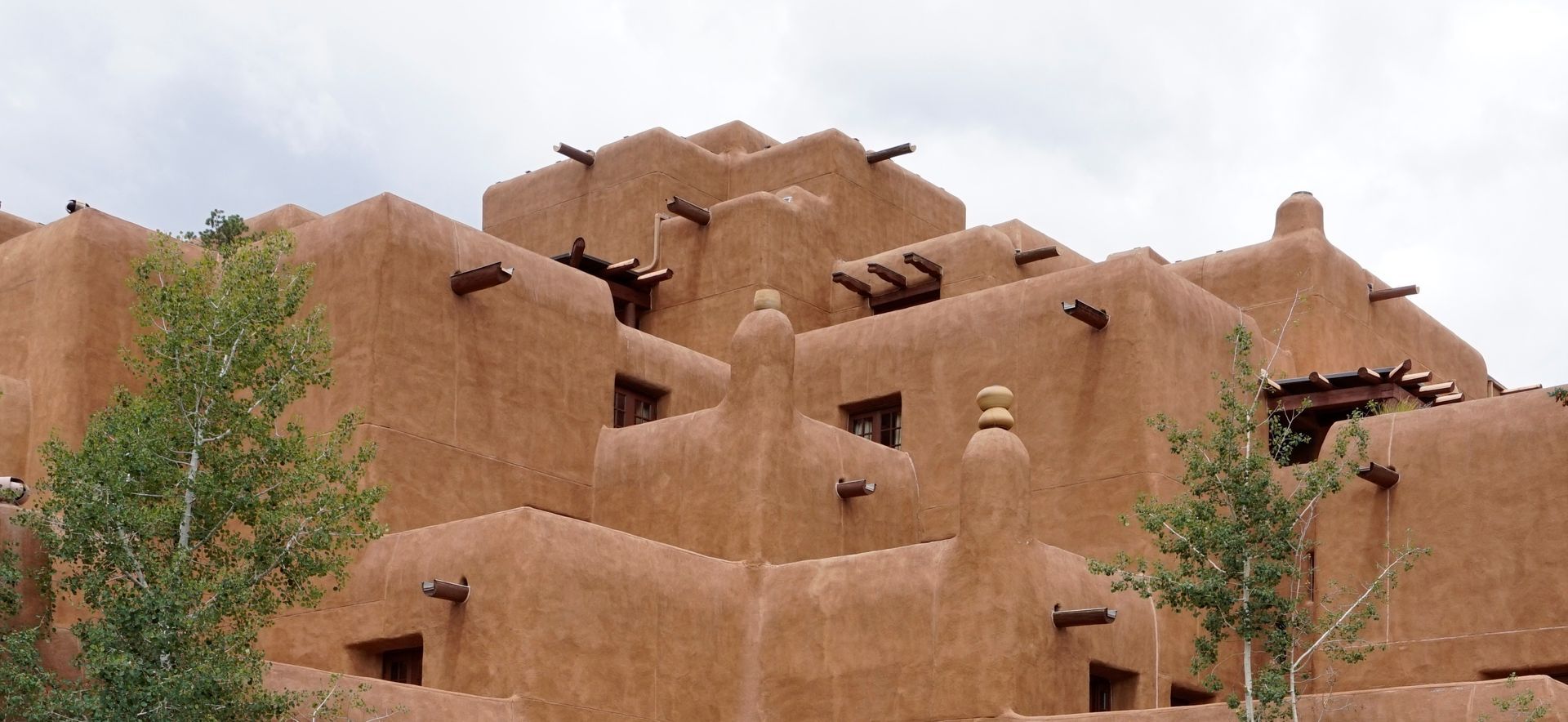 Adobe-style mud-brick building with stepped walls and small windows under a cloudy sky Adobe-style mud-brick building with stepped walls and small windows under a cloudy sky