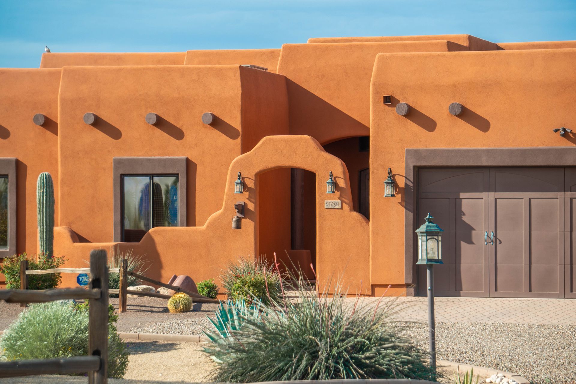 Adobe-style orange house with arched entry, garage, and desert landscaping