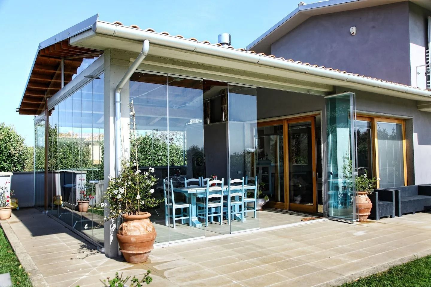 Patio coperto vuoto con pareti beige, pavimento piastrellato e porta di sicurezza scorrevole in metallo.