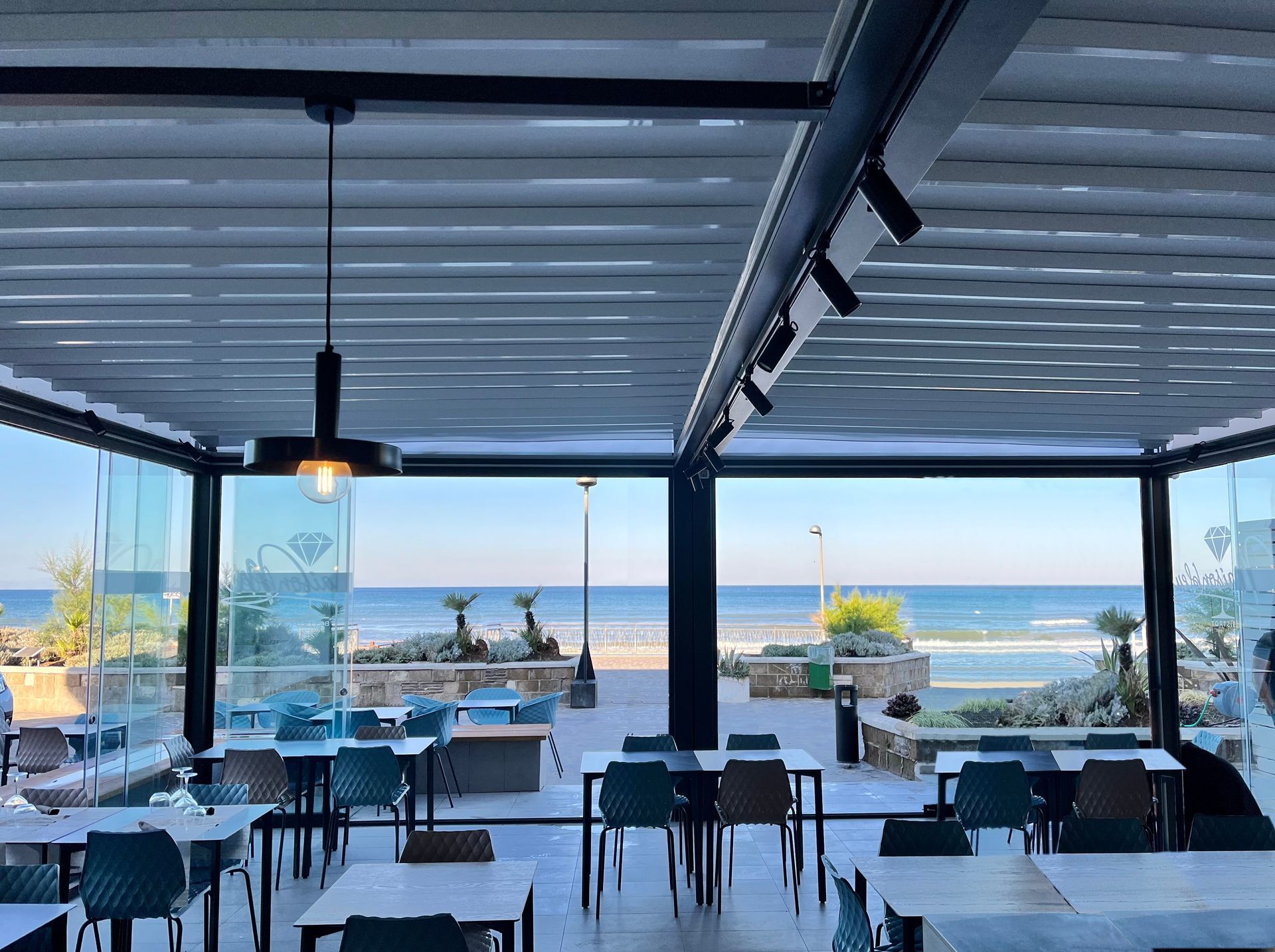 Ristorante all'aperto sul mare con tavoli che si affacciano sull'oceano al tramonto