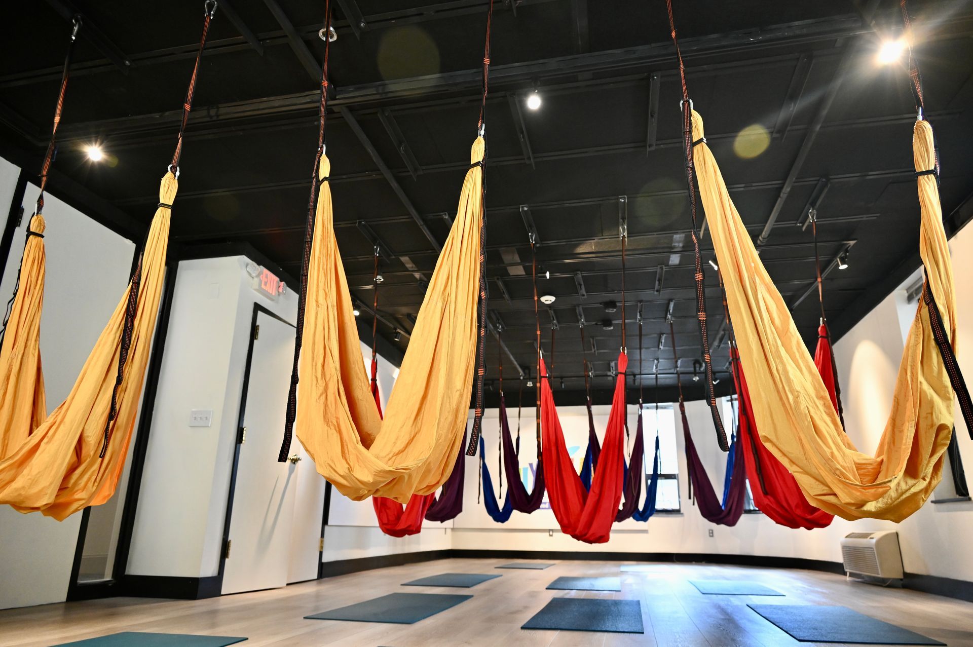 Inside the aerial yoga studio at Yoga@Play — rainbow silks and hammocks