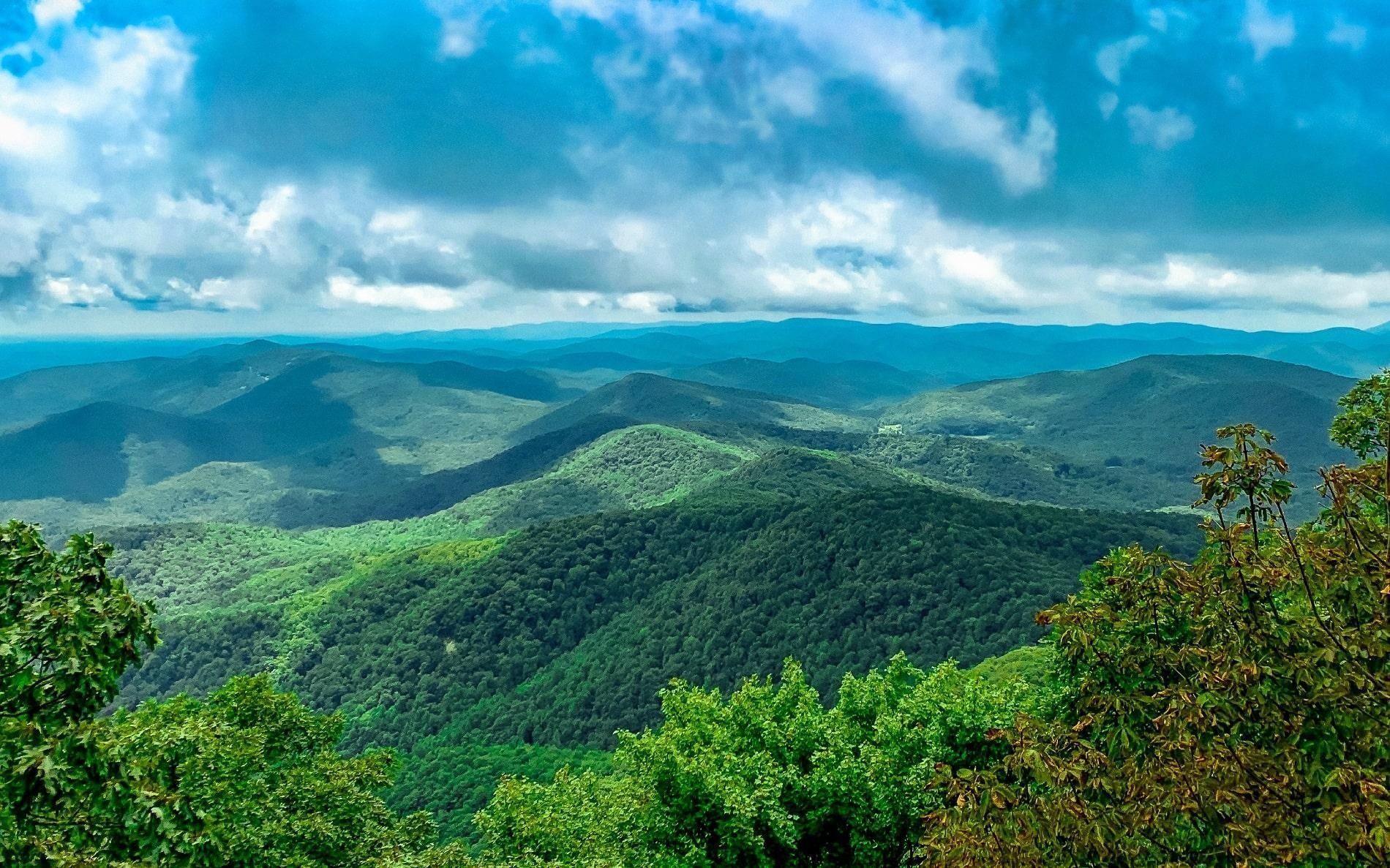Rolling green mountain range under a partly cloudy sky.