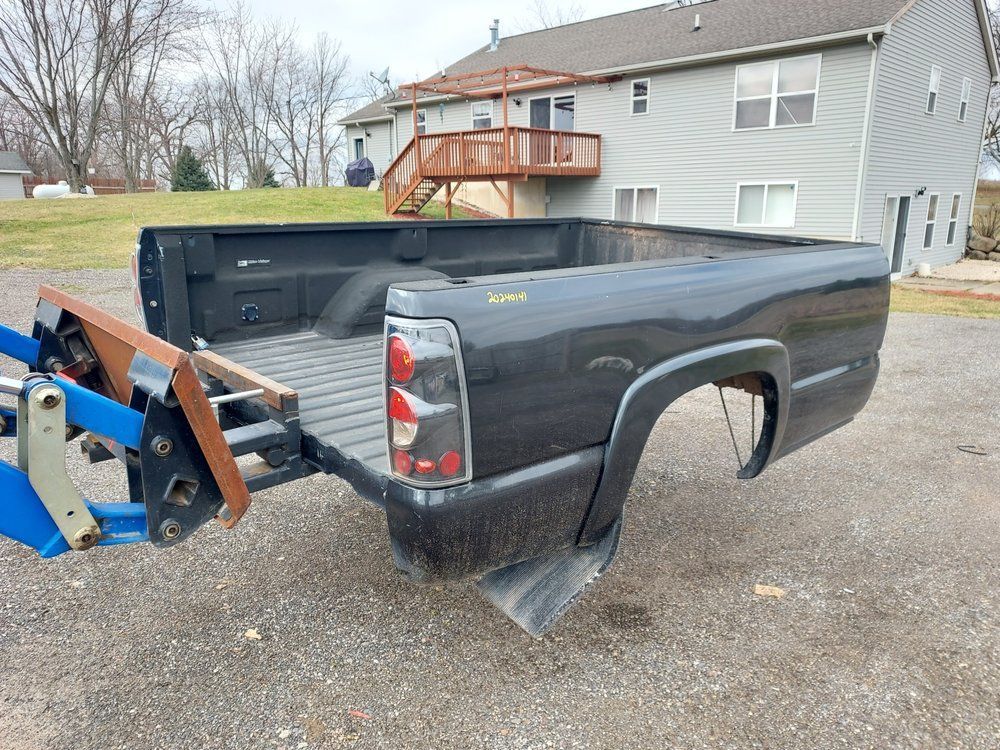 A truck bed is sitting on the ground in front of a house.