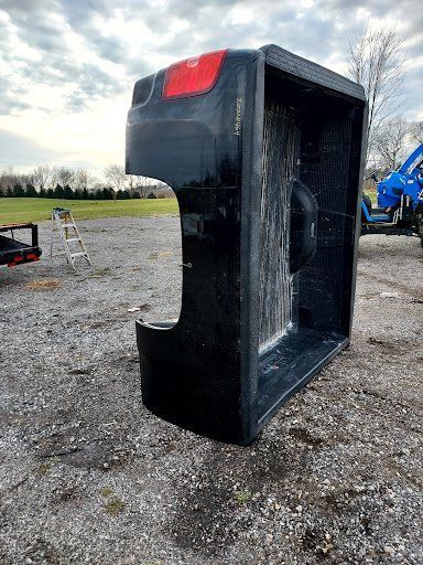 A black truck bed is sitting on top of a gravel road.