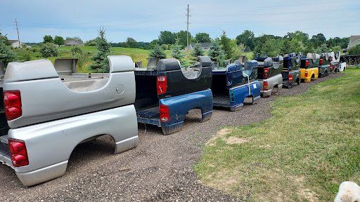 A row of truck bed covers are lined up in a field.