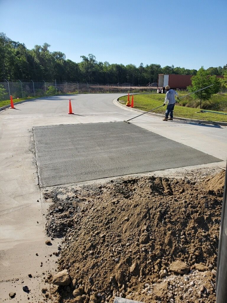 A man is standing next to a pile of dirt on the side of a road.