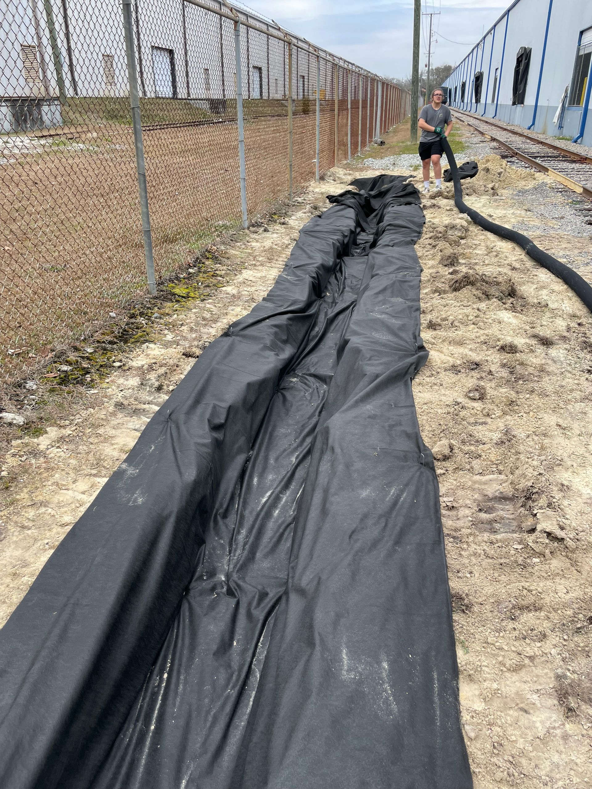 A man is standing next to a large black tarp.