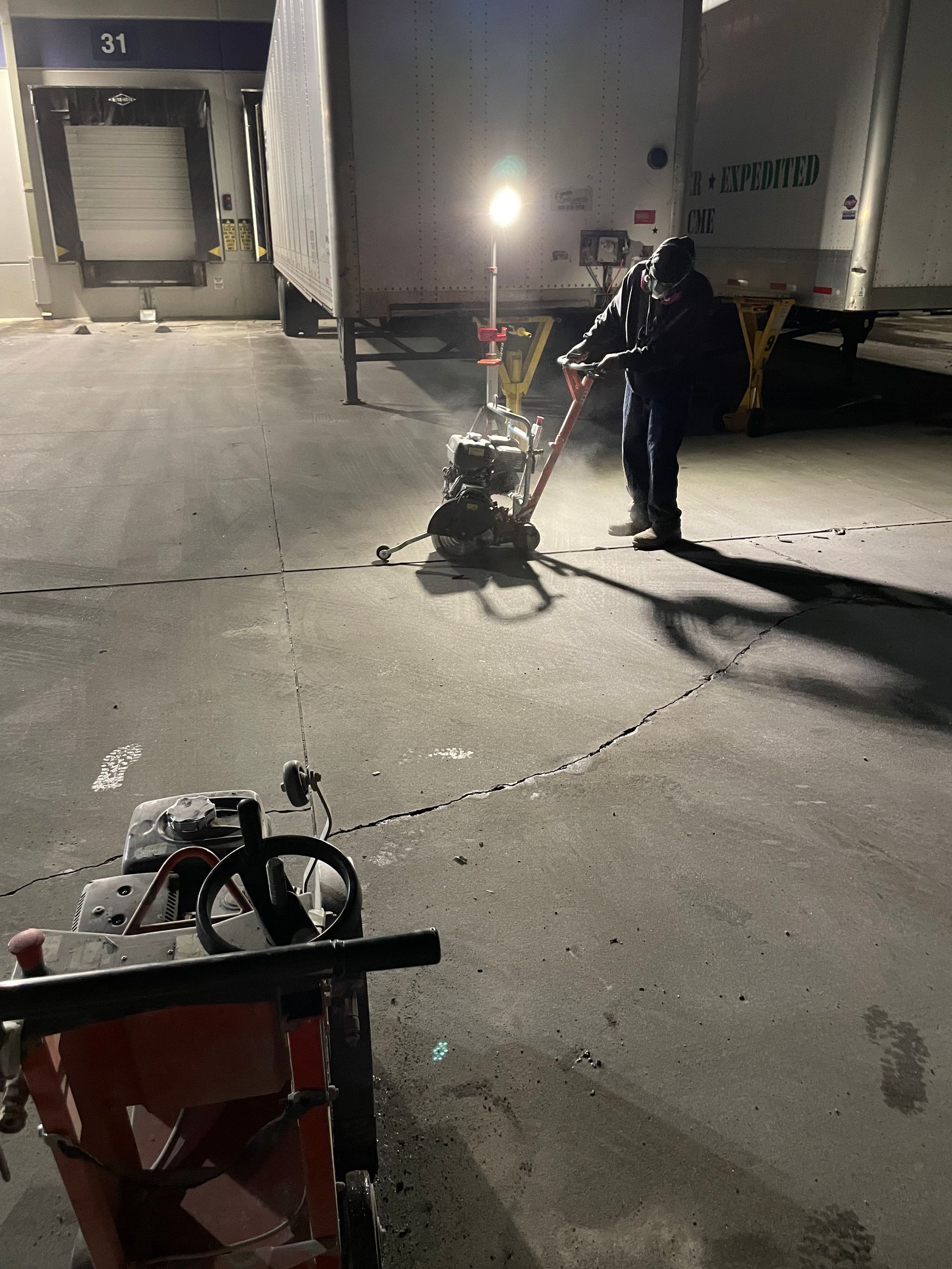 A man is standing next to a machine in a parking lot at night.