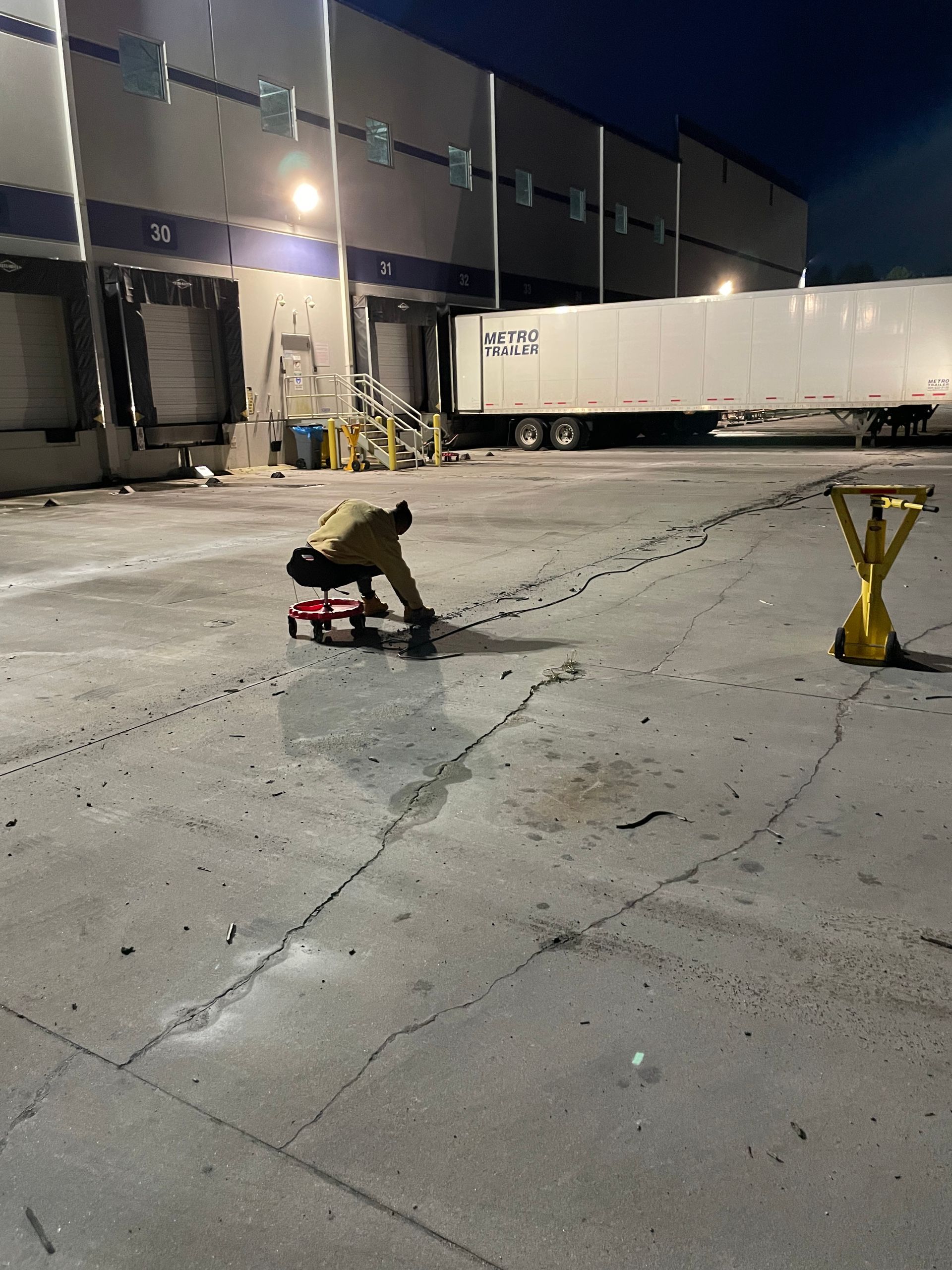 A man is kneeling down in front of a warehouse at night