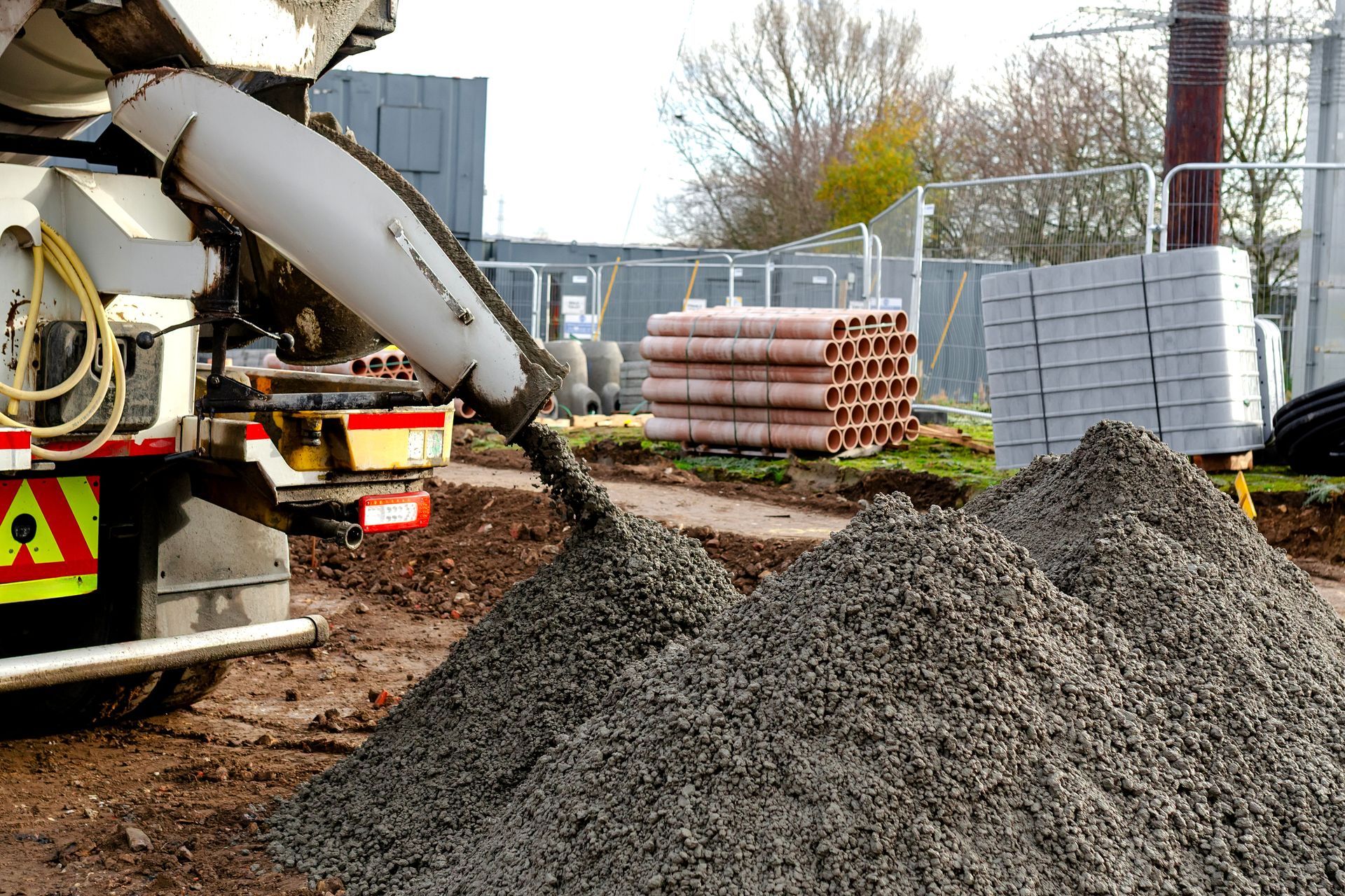 A truck is unloading a semi-dry concrete mix into a ground pile at the site.