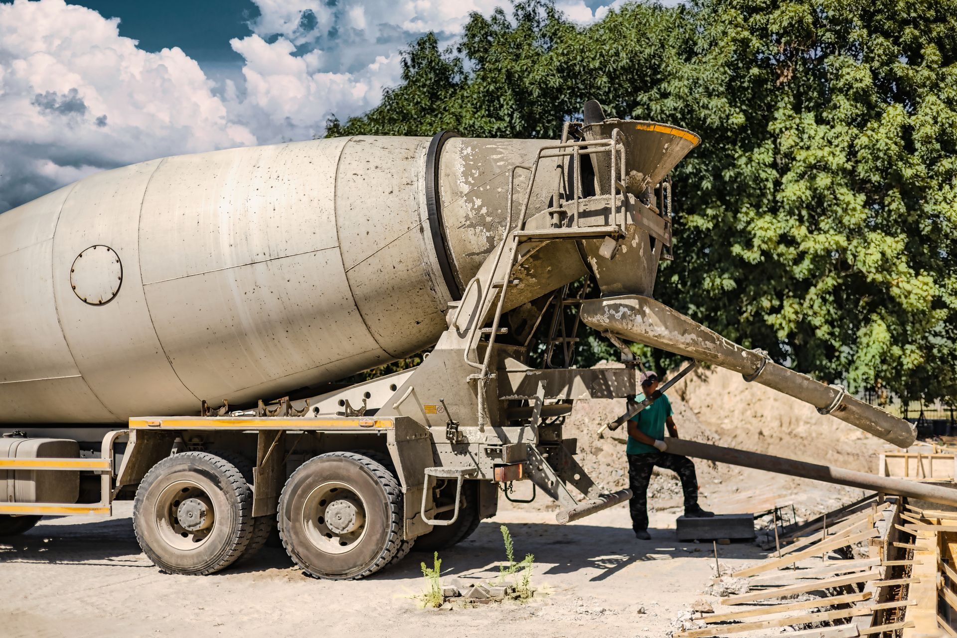 Concrete delivery service mixer truck pouring ready-mix down a chute into foundation forms