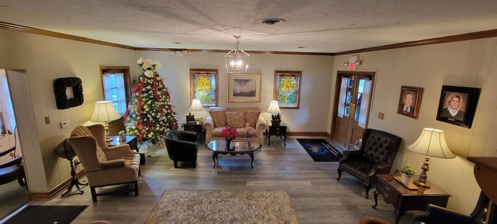 Cozy living room with seating, a Christmas tree, and stained glass windows.