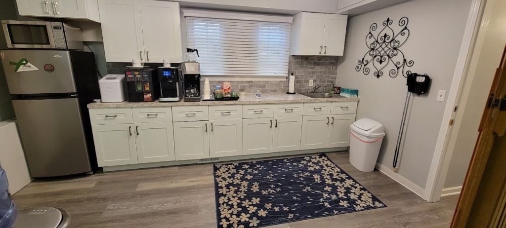 Kitchen with white cabinets, stainless steel fridge, and a rug.