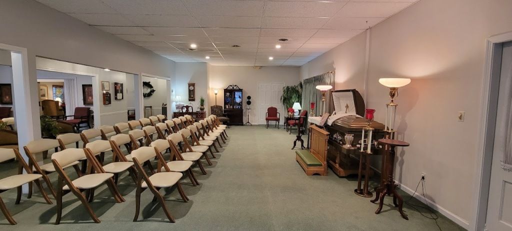 Interior of a funeral home with rows of chairs, decor, and a casket.