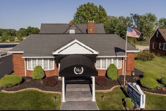 Red brick funeral home with black awning and American flag.