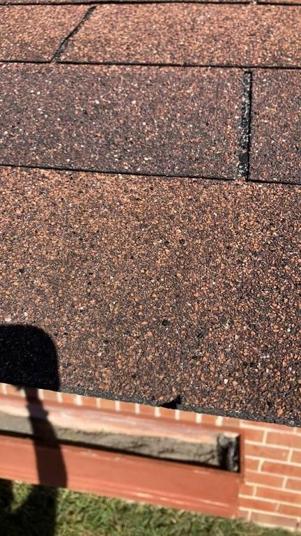 A close up of a roof with a brick wall in the background.