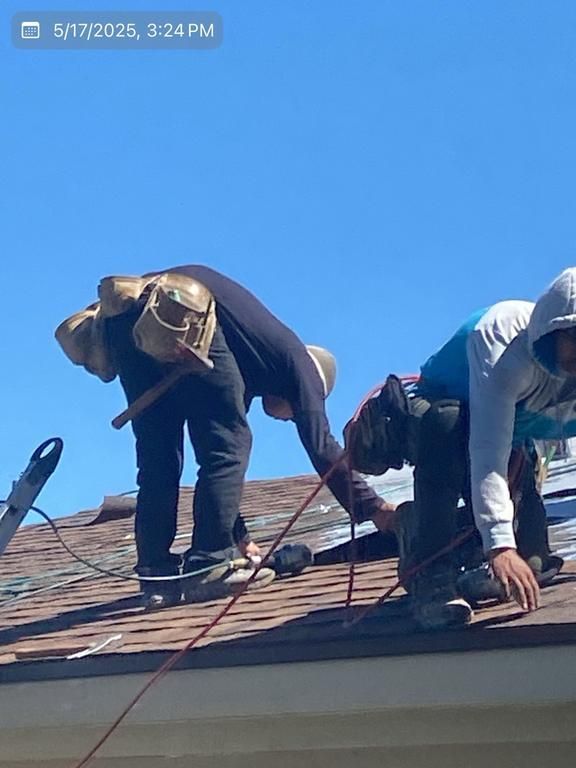 Two men are working on the roof of a house