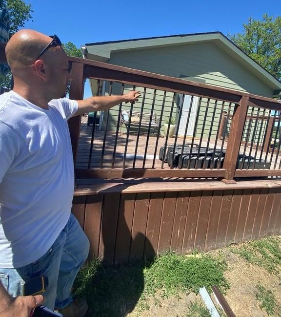 A man in a white shirt is pointing at a wooden deck